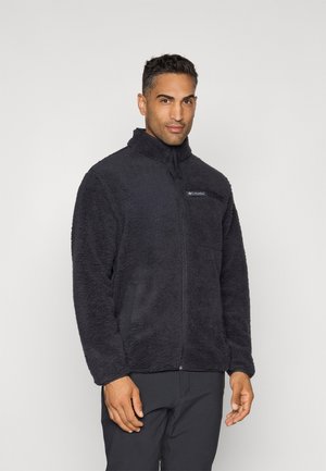 Black fleece jacket with a high collar, zip closure, and logo patch on the chest. Features a soft, textured fabric and side pockets.