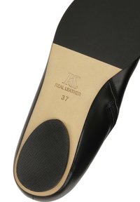 Sole di scarpa in pelle nera con un sottopiede beige liscio, caratterizzato da un'incisione "VERA PELLE" e dalla taglia "37". Grip in gomma testurizzata sul tallone.