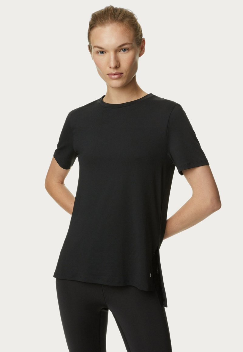 Camiseta negra de manga corta hecha de tela suave, con un escote redondo y aberturas laterales para facilitar el movimiento.