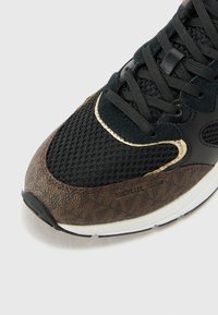 Black and brown sneaker with mesh upper, suede accents, and textured brown overlay. Features round laces and rubber outsole.