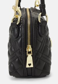 Svart quiltad handväska med guldfärgad metalldetaljer, dubbla dragkedjor och en berlock med ordet "LOVE" och en hjärtemblem.