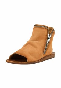 Sandale plate ouverte à l\'orteil en cuir marron clair avec une fermeture éclair latérale et un dessus souple plissé.