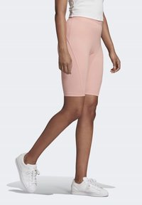 Ljust rosa cykelbyxor med en slät textur, hög midja och sid söm detaljer, bärs med vita sneakers, vilket visar en avslappnad look.