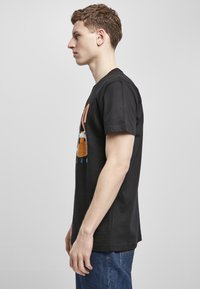 Svart bomull t-skjorte med grafisk trykk av en basketball og tekst på forsiden, kortermer, og en avslappet passform.