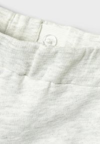 Ceinture en tissu gris clair avec une texture lisse et un bouton transparent circulaire pour la fermeture, ornée d'un motif légèrement côtelé.