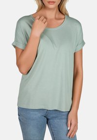 T-shirt à manches courtes vert menthe en tissu doux avec un col rond, présentant des poignets roulés et une coupe décontractée.