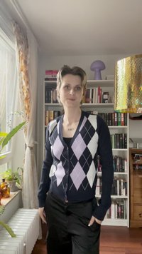 Tamno plavi kardigan s bijelim i lavandom dijamantnim uzorkom, s prednjim kopčanjem i dugim rukavima. Nosite preko crne bluze, u kombinaciji s crnim hlačama.