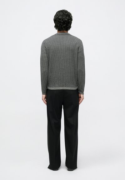 Pelēks teksturēts džemperis ar brīvāku piegriezumu un ribotiem aprocēm, kombinēts ar melnām, platām biksēm. Nav redzamu rakstu vai dizaina elementu.