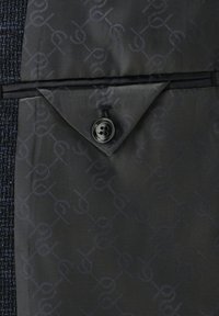 Black button closure and flap pocket on textured navy fabric with a subtle pattern. Smooth lining features a repeating logo.