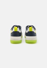 Back view of navy sneakers with lime green soles. Features mesh and synthetic materials, padded collars, and brand logo on the heel.