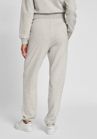 Grå sweatshirtbyxor gjorda av en blandning av bomull med en tapered bendesign, elastisk midja och resårer, tillsammans med vita sneakers.