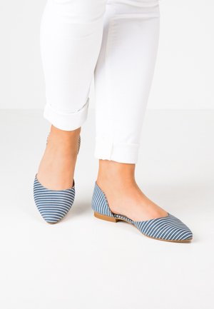 Blaue und weiße, gestreifte Ballerinas mit spitzer Zehe, niedrigem Absatz und ausgeschnittenen Seiten, kombiniert mit weißen, hochgekrempelten Hosen auf einem neutralen Hintergrund.