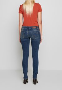 Slim jeans i mörkblå denim med en mjuk textur, med bakfickor och en märkesläderlapp vid midjan.