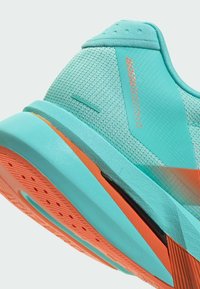 Κοντινή λήψη της φτέρνας του παπουτσιού Adizero Boston 13 σε τιρκουάζ και πορτοκαλί με υφή στη σόλα και λεπτομέρειες από δίχτυ στο πάνω μέρος.
