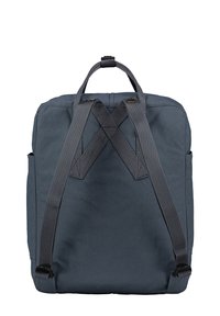 Dark blue backpack with a square shape, made of durable fabric. Features adjustable gray straps and a looped handle on top.