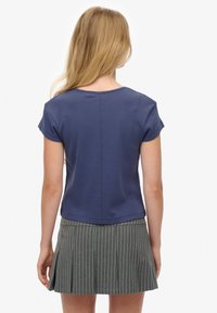 Camiseta de algodón azul marino de manga corta, con escote redondo y un corte casual, combinada con una falda plisada gris a rayas.