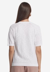 Kortärmad vit stickad topp med texturerad yta, raglanärmar och ribbade mudd och nederkant. Designad med en avslappnad passform.