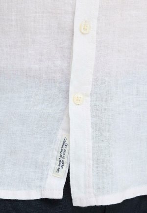 Valge tekstuuriga särgi eesosa, millel on kaks valget nuppu ja kangasmärgiga silt, millel on kirjas "See võib olla täiuslik peenearsti ühendus."