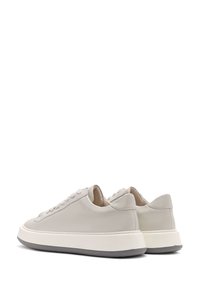 Baskets en cuir gris clair avec bout rond, design à lacets plats, languette rembourrée et épaisse semelle blanche avec des accents gris.