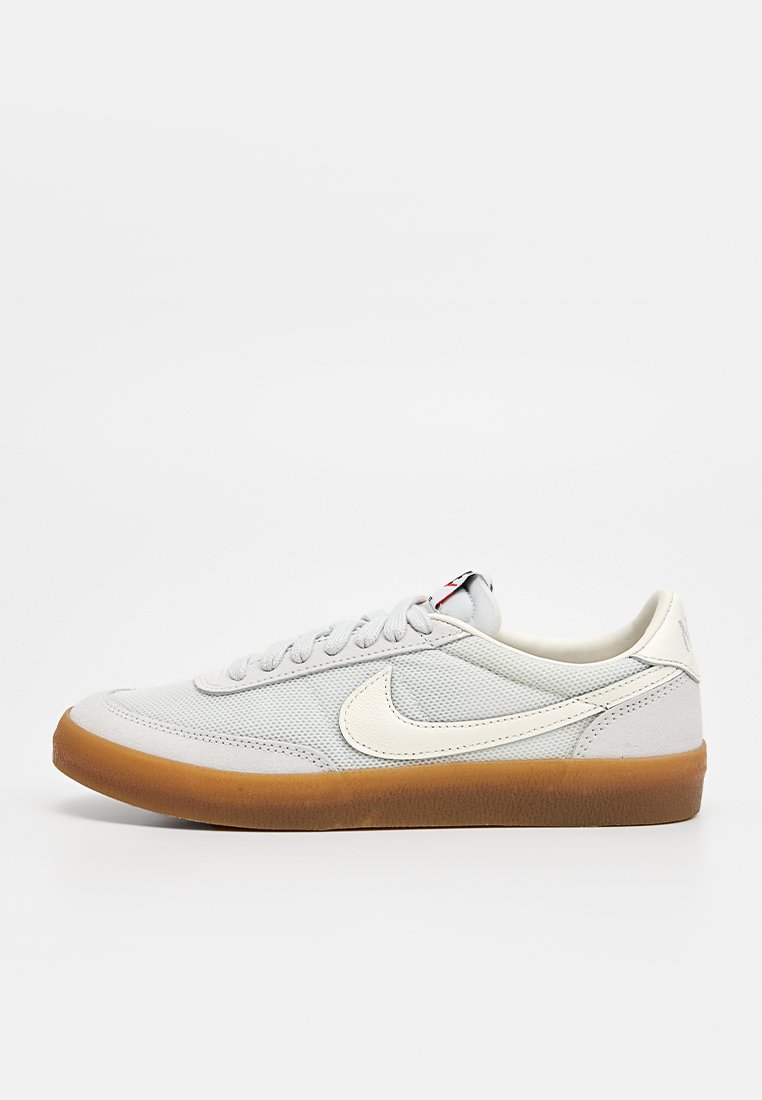 Zapatillas gris claro con un upper texturizado, logo Swoosh blanco y suela de goma. Presentan cordones planos y un diseño minimalista.