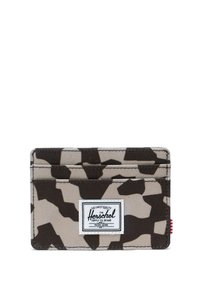 Maastokuvioitu kangaskorttikotelo, jossa on kolme taskua ja valkoinen suorakaiteen muotoinen merkki etupuolella, jossa lukee "Herschel Supply Co. Brand".