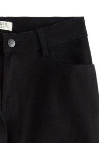 Jeans in denim nero con chiusura a bottone, tasche standard e cuciture visibili. Il materiale è liscio con una leggera lucentezza.