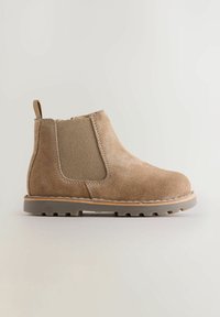 Bottines en daim marron avec des panneaux élastiques sur les côtés, une languette de tirage et une semelle en caoutchouc, présentant un bout rond et une surface texturée.