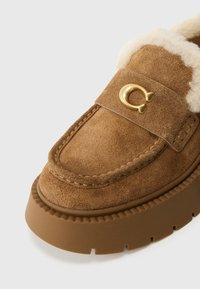 Barna színű velúr bebújós cipő bolyhos belső résszel, arany színű díszítéssel és vastag, barázdált gumitalppal.