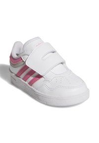 Baskets blanches avec des accents roses et argentés, présentant une finition en cuir lisse, un design à trois rayures et une fermeture à bande Velcro.