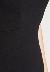 Černé úzké šaty s hladkou texturou, obsahující strukturované švy a design pasového panelu, který zdůrazňuje elegantní siluetu.