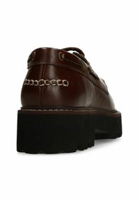Bruine leren schoen met een stevige zwarte zool, voorzien van een kettingsteekdetail op de achterkant, metalen oogjes en een vetersluiting.