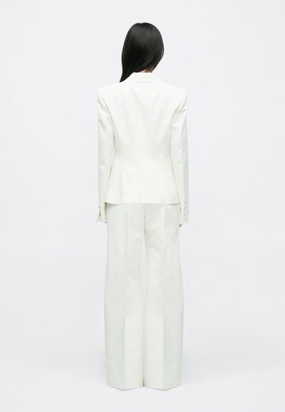 Witte op maat gemaakte outfit met een gestructureerd colbert met een getailleerde taille en broek met wijde pijpen. Glad stof met minimale details.