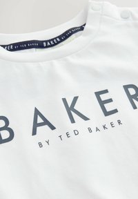 Weißes Baumwoll-T-Shirt mit rundem Ausschnitt und Druckknöpfen; mit fettem schwarzem Text "BAKER" und kleinerer Schrift "by TED BAKER".