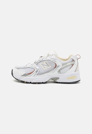 White and grey New Balance athletic shoe with mesh panels, cushioned sole, lace-up front, and beige inner lining, shown from the side.