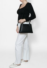 Zwarte leren handtas met een gestructureerde vorm, uitgerust met een bovenhandgreep en een verstelbare schouderband. Gelaagde oppervlakte met een minimalistisch ontwerp.