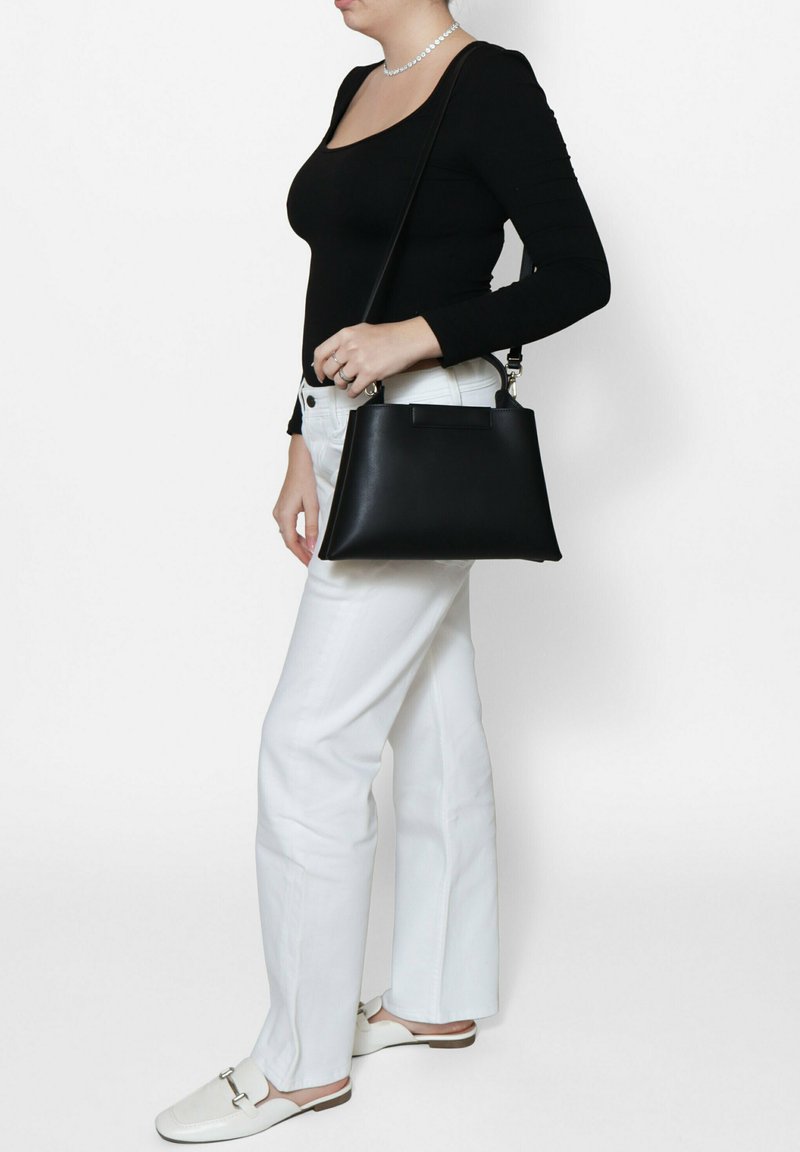 Zwarte leren handtas met een gestructureerde vorm, uitgerust met een bovenhandgreep en een verstelbare schouderband. Gelaagde oppervlakte met een minimalistisch ontwerp.