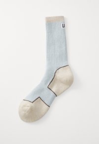 Calzino blu chiaro a coste con una fodera e un tallone beige. Presenta cuciture di accento marroni e un logo sul lato. Tessuto morbido.