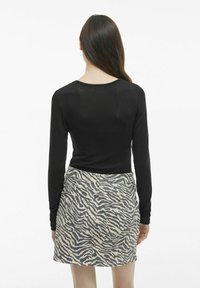 Svart långärmad topp kombinerad med en beige kjol med svart zebramönster. Outfitten är åtsittande och casual i stilen.