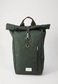 Pyöröaukkoinen vihreä reppu, joka on valmistettu kestävästä kankaasta. Siinä on edessä vetoketjullinen tasku, metalliosat ja yläkahva kantamista varten.