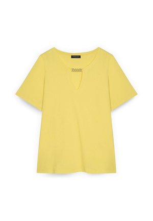 Žlutá košile s krátkým rukávem, kulatým výstřihem a malým klíčovým otvorem na přední straně, připevněným stříbrným ozdobným řetízkem.