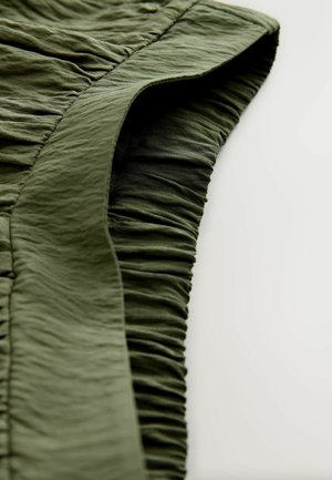 Olivzaļš audums ar savelkamu faktūru un gludu malu. Materiāls izskatās viegls un nedaudz krokains.