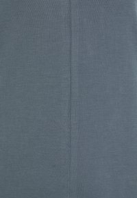 Tessuto di cotone blu con una texture liscia, caratterizzato da una cucitura centrale che corre verticalmente. Il materiale appare leggero e traspirante.