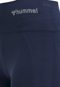 Mørkeblå atletiske leggings lavet af strækbart stof med et ribbet design og en elastisk talje med et gråt "hummel" logo.