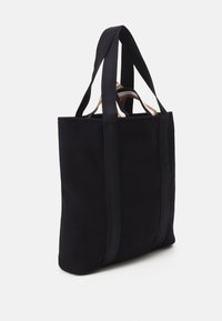 Svart canvas-tygkasse med dubbla handtag upptill. Rektangulär form, minimalistisk design utan synliga beslag eller mönster. Texturerat tyg.