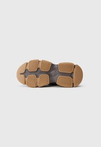 Talpa unei pantofi cu o suprafață texturată de culoare gri închis, cu modele de traction din cauciuc și un tread în zigzag de culoare miere pentru aderență și durabilitate.
