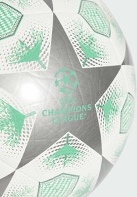 Champions League soccer ball featuring white, black, and green panels with geometric patterns and a textured surface; logo displayed centrally.