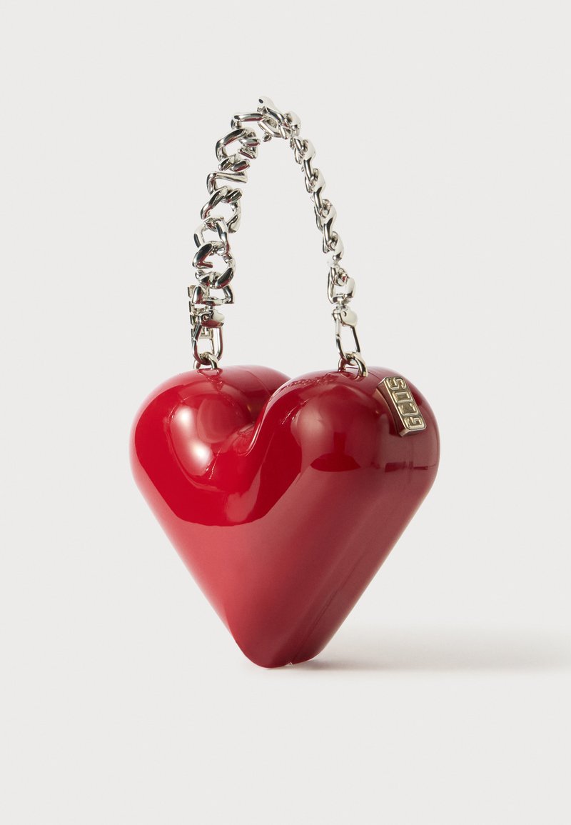 Rød hjerteformet håndtaske lavet af glat materiale, med et metallisk sølv kædehåndtag og en lille mærkeaccent.