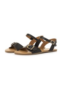 Schwarze flache Sandalen mit hellbrauner Sohle, ausgestattet mit einem Riemen über den Zehen und einem verstellbaren Knöchelriemen mit goldfarbenen Schnallen.
