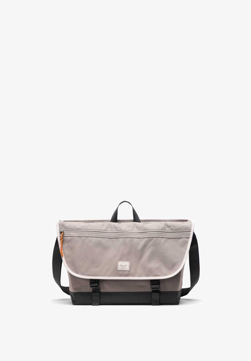 Grijze stoffen schoudertas met een handvat aan de bovenkant, zwarte basis, verstelbare schouderriem, voorklep met sluiting en een oranje ritsdetail.