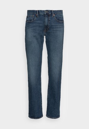 Denim jeans in dark blue, straight-leg cut. Features five pockets, copper hardware, and subtle whiskering on the front. Smooth texture.